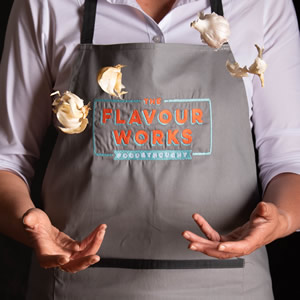 Someone wearing a Flavourworks apron, juggling cloves of garlic